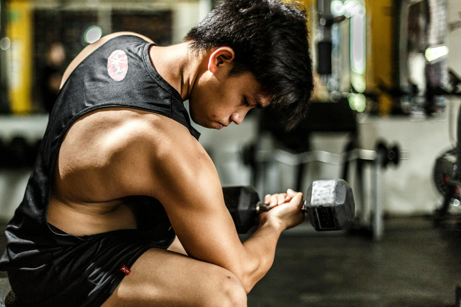 A man squats while performing a bicep exercise with a dumbbell, focusing on strength training and muscle development.